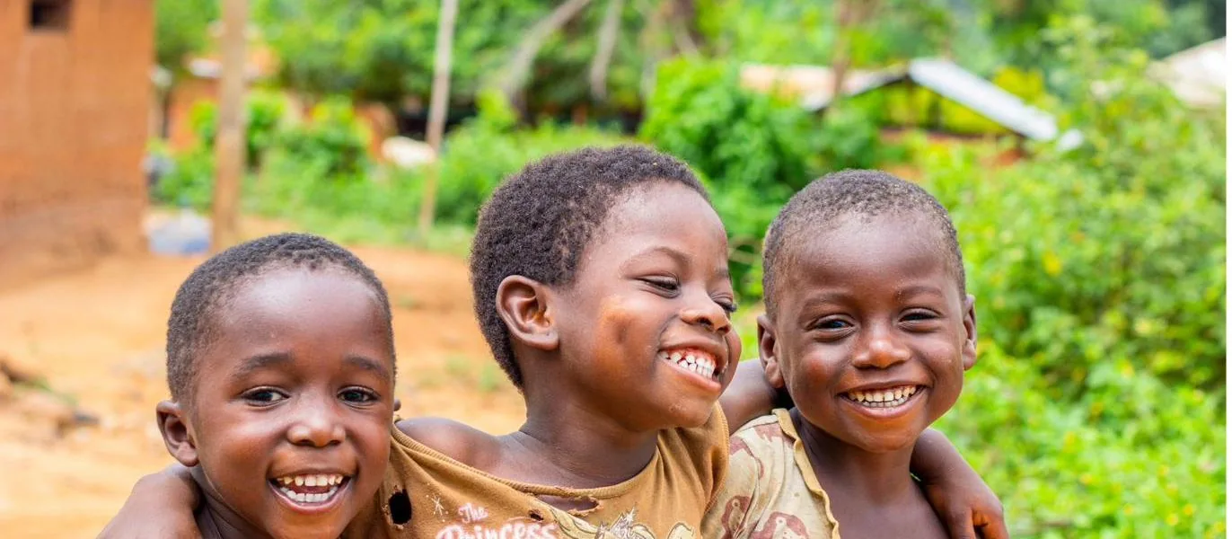 Three smiling children with arms around each other